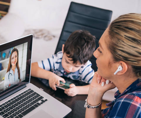 woman watching professional screencast with earbuds and child nearby