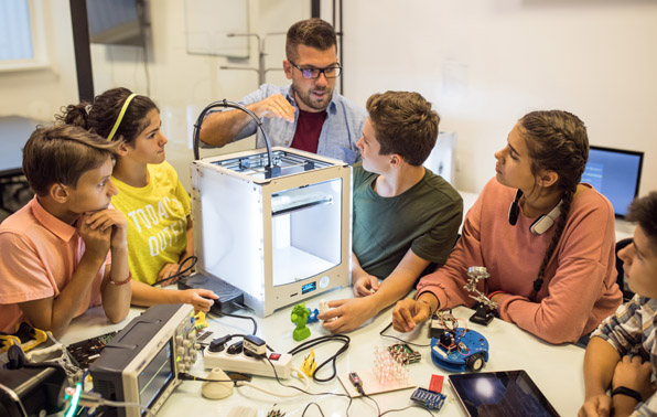 teacher working with students using a 3D printer